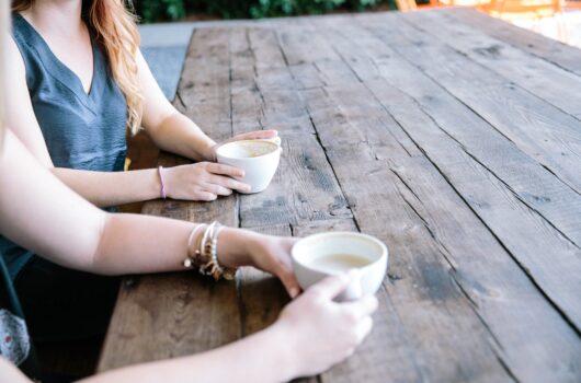 Two people drinking hot drinks on table- Gordon moody